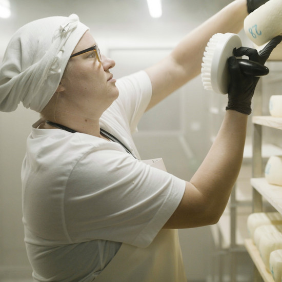 Eine James Farm Mitarbeiterin putzt den Käse